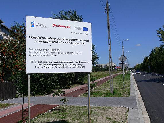 Tablica informacyjna o wykorzystaniu funduszy UE na budowę drogi.